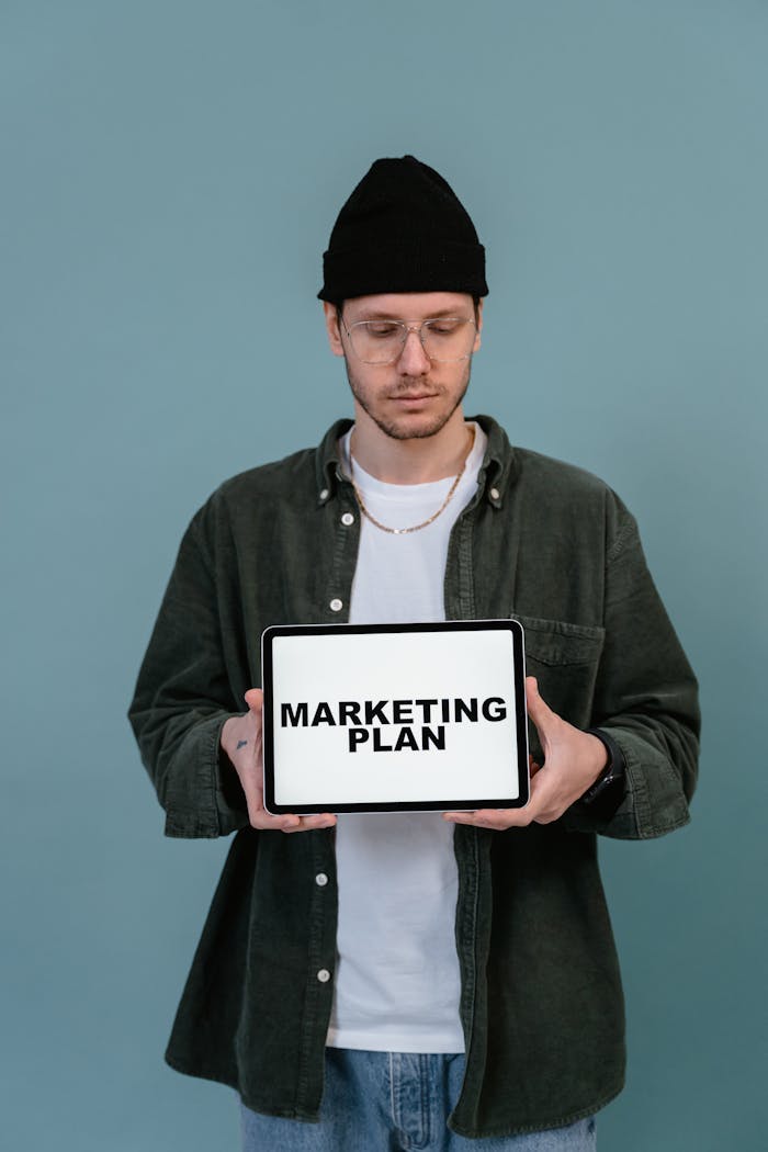 services-02 Adult wearing casual clothing holding a tablet that reads Marketing Plan.